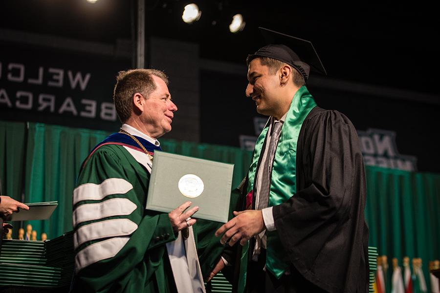 Northwest President Dr. Lance Tatum congratulates Didar Orazgeldiyev, 谁毕业于以视觉成像为重点的数字媒体学士学位, on the commencement stage Friday afternoon. (Photos by Lauren Adams/Northwest Missouri State University)